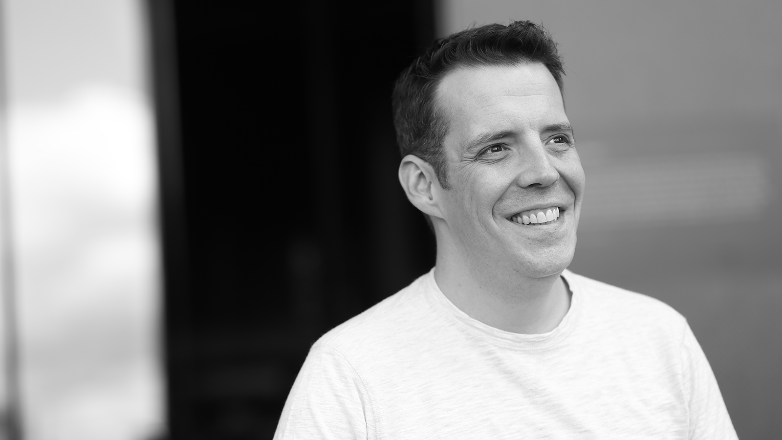Conductor Matthew Goinz smiles in a black and white photo.