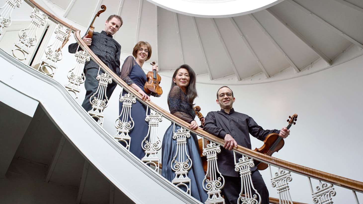 Members of Brentano String Quartet pose on stairs with instruments.