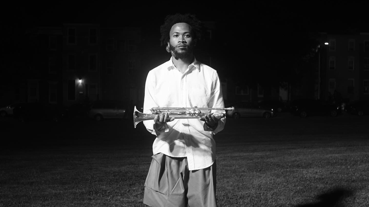 Brandon Woody poses with trumpet outside.