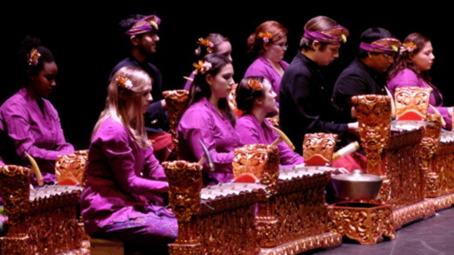 Students in traditional clothing perform on stage. 