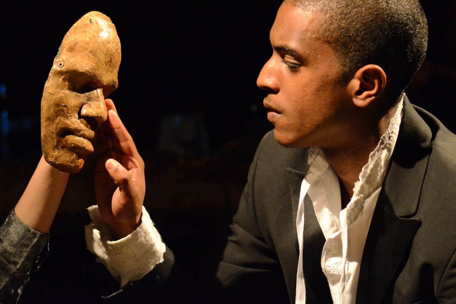 A man touches a clay face mask.