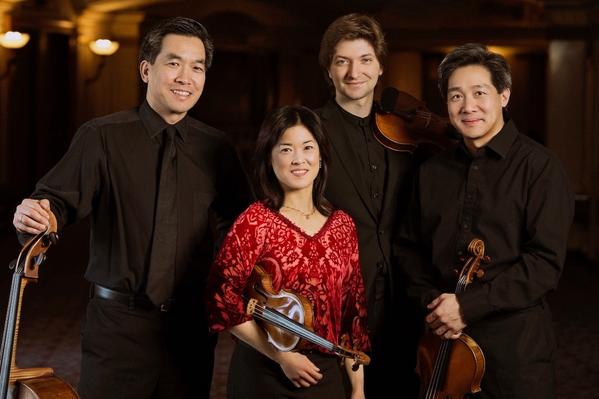 Four people pose with their string instruments.