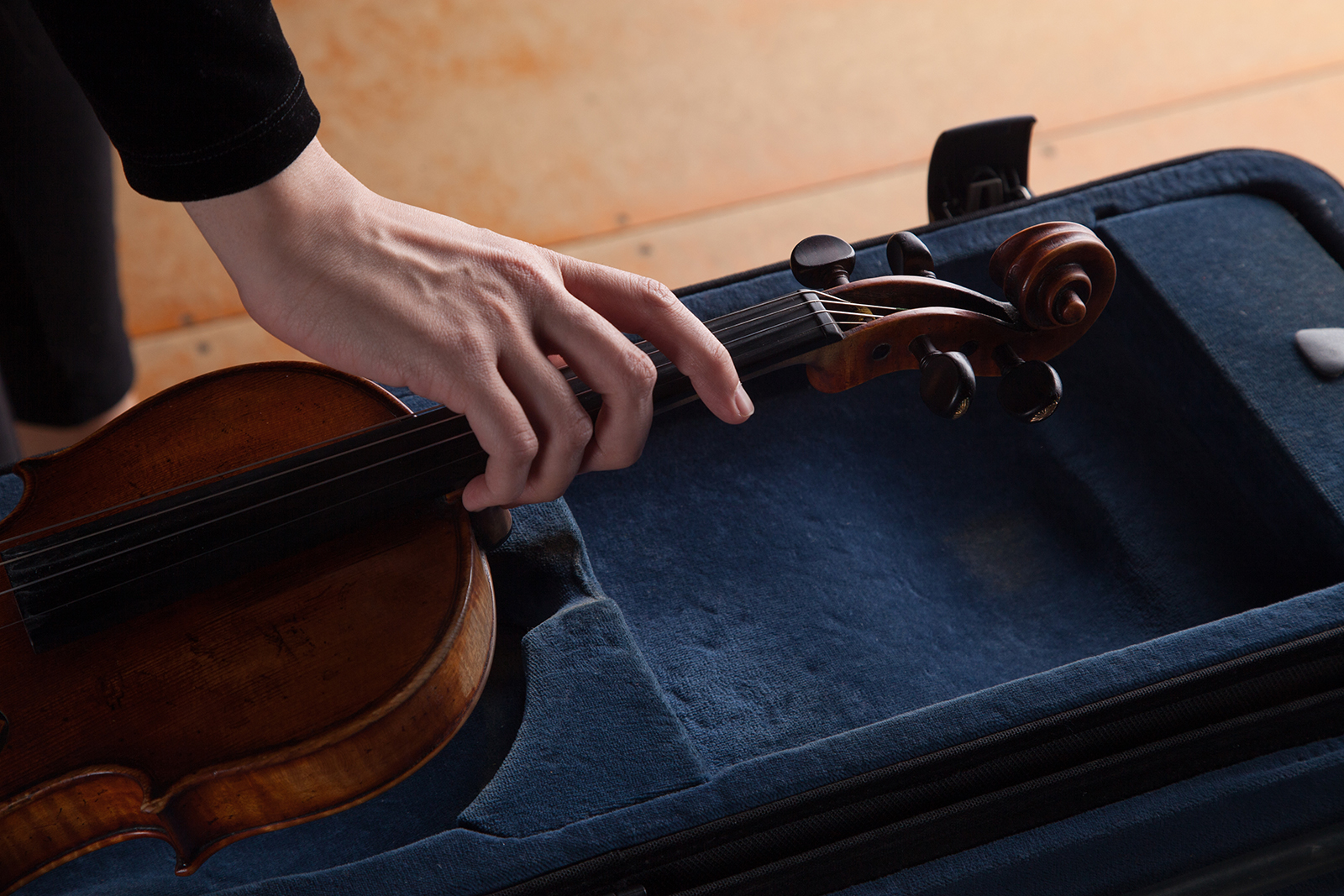 A hand pulls a violin out of it's case.