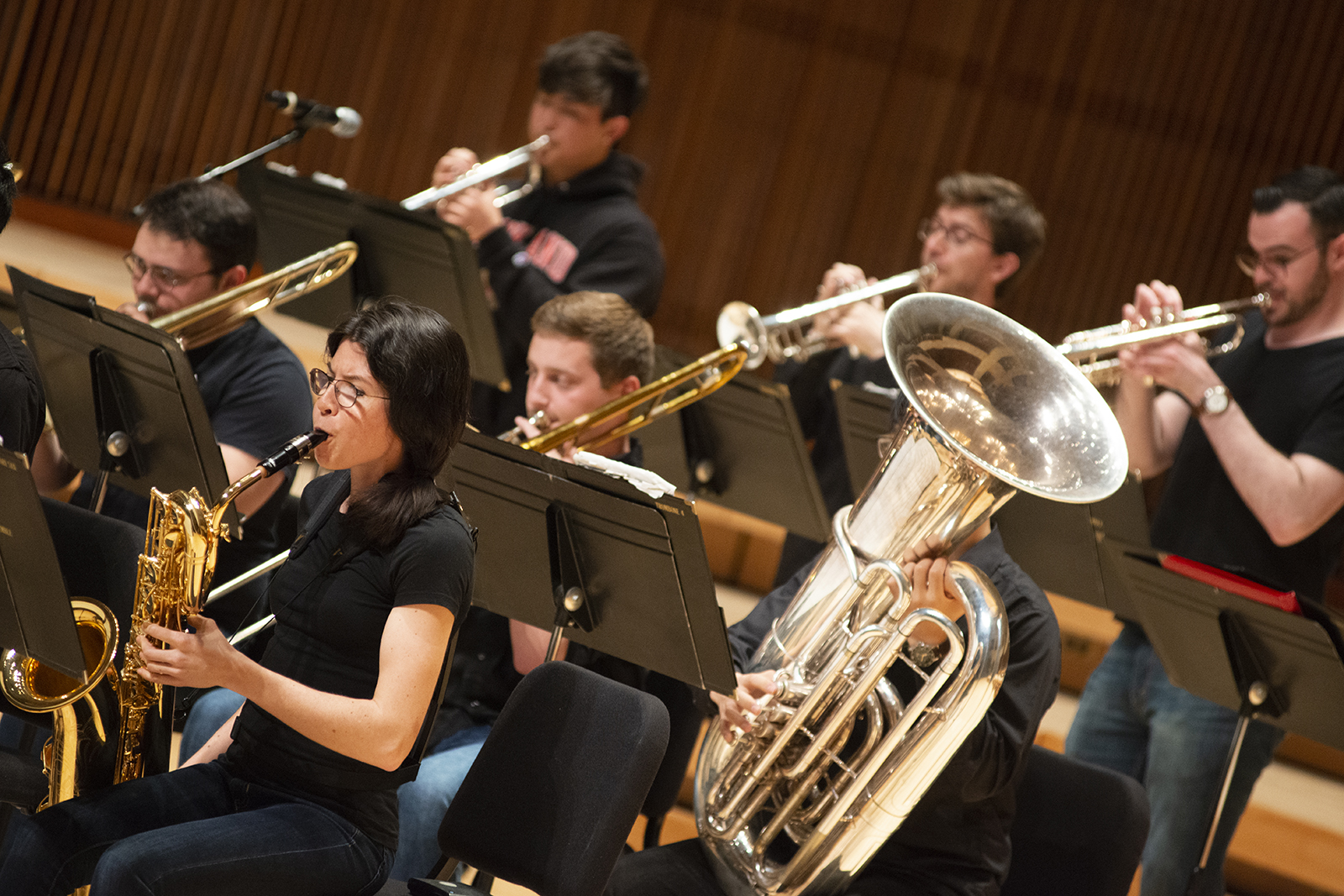 Men and women play brass instruments during a performance.