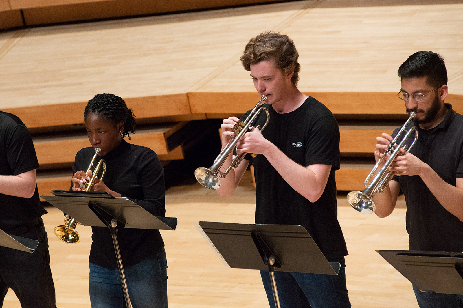Three students play trumpets during a concert.