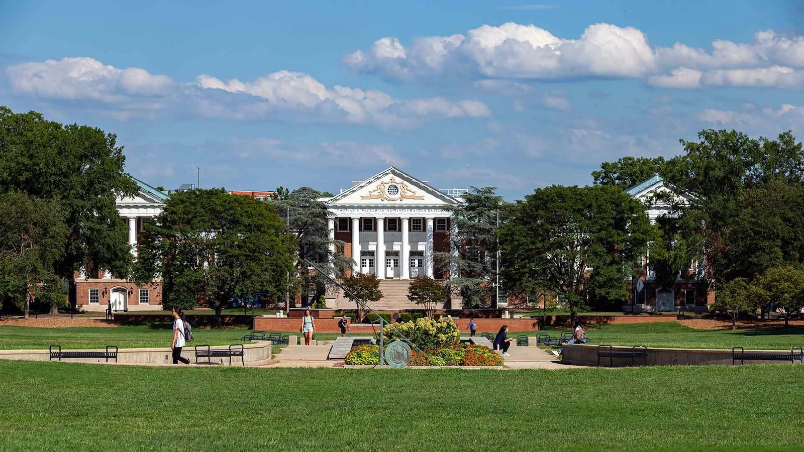 Students walking outside on a sunny day in front of the UMD main administration building.