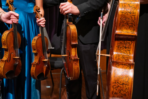 Image of three people's hands holding instruments upright.
