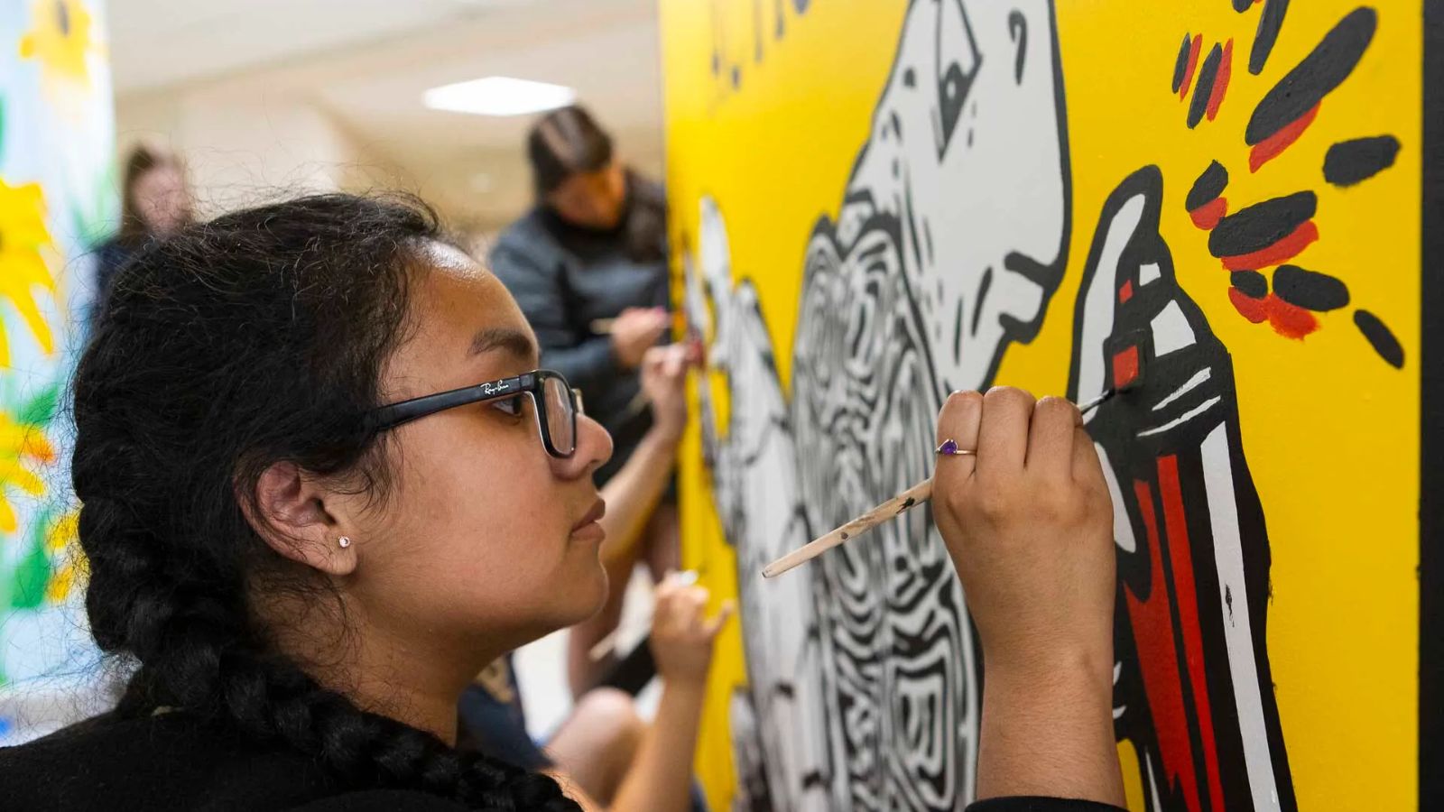 A student paints the Terp Takes Action mural.