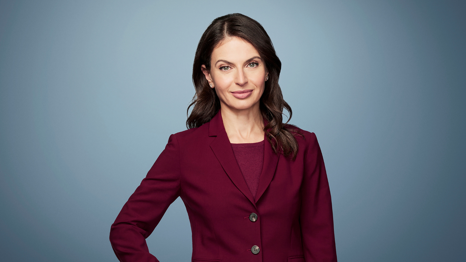 Photo of Bianna Golodryga in a maroon suit coat on a light blue background.