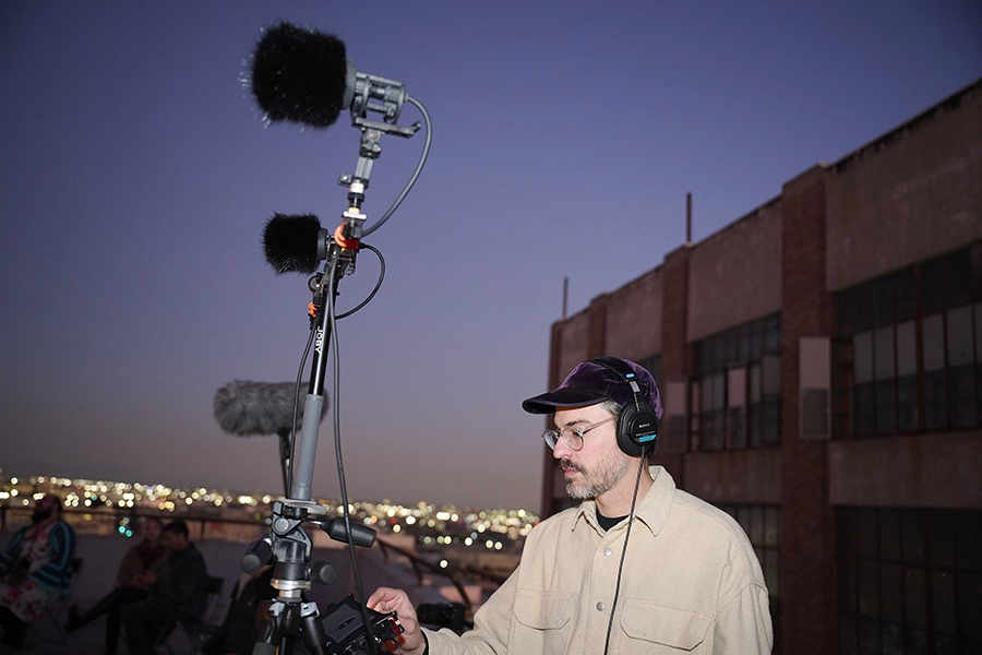 Photo of visiting artist Ben Kinsley standing on a building with a boom mic