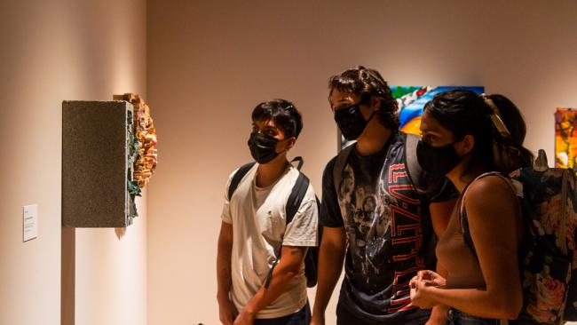 A group of students looking at a piece of art at the art exhibition